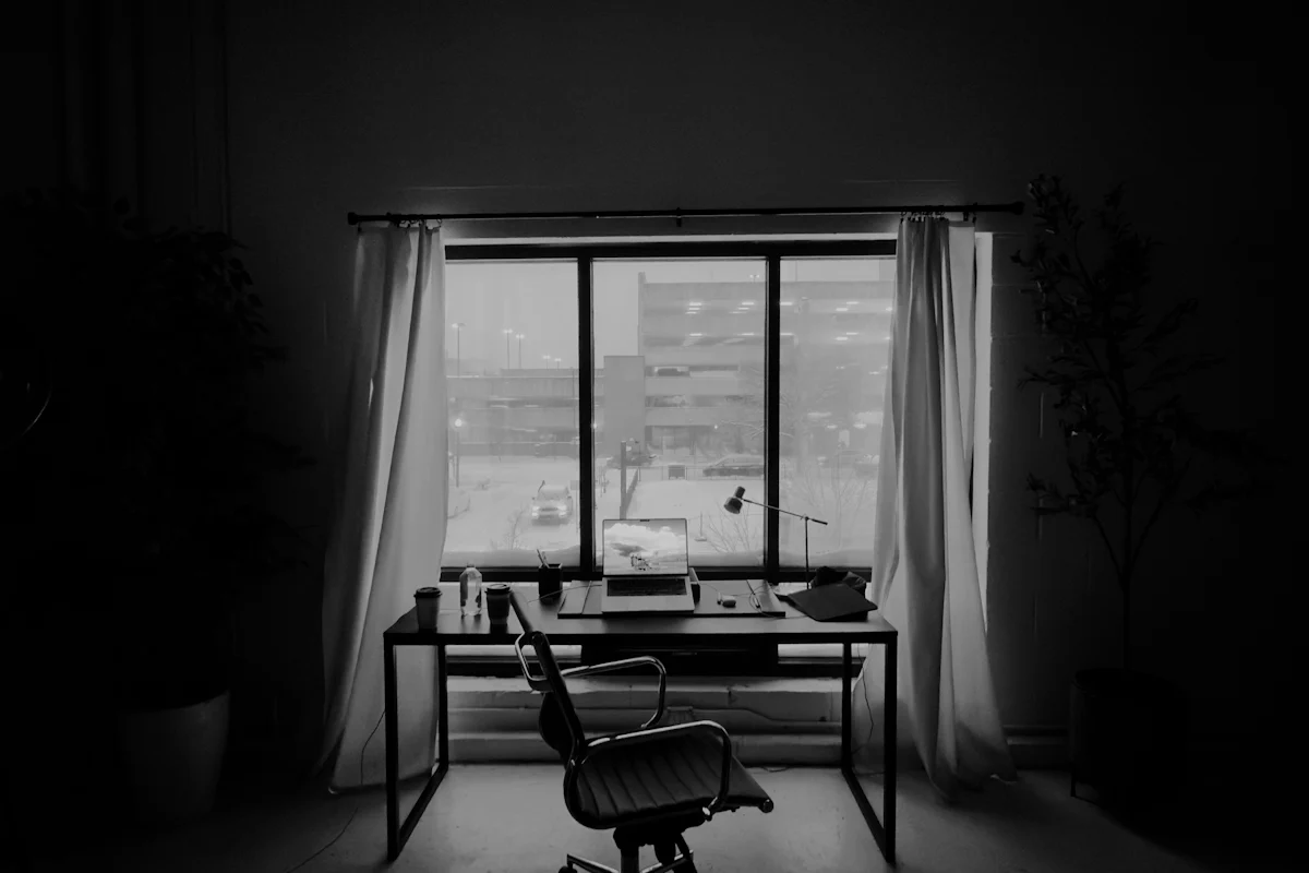 An empty office desk with a closed-down workspace in front of a window, for a post on explaining a layoff in an interview