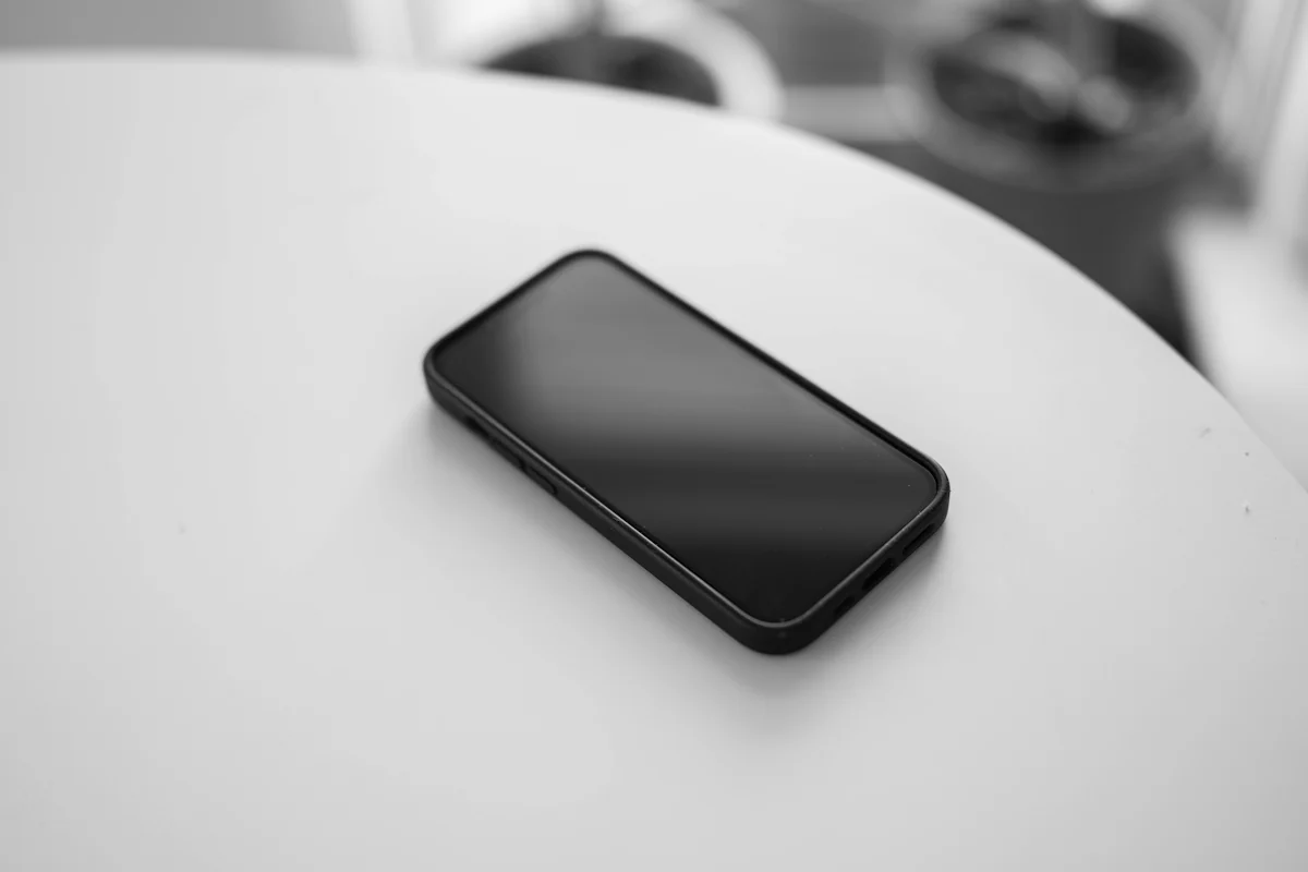 A smartphone lying face up on a white table, illustrating offline sync duplicates after a retry