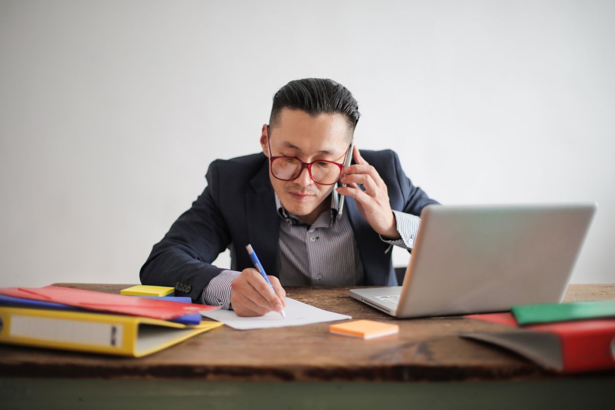 An engineer taking notes during an Android recruiter screen phone call at a desk with a laptop
