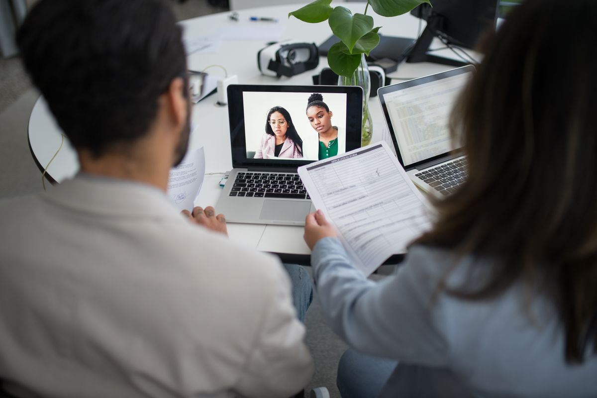 Two interviewers looking at a resume while on a video call with a candidate during an Android hiring manager screen