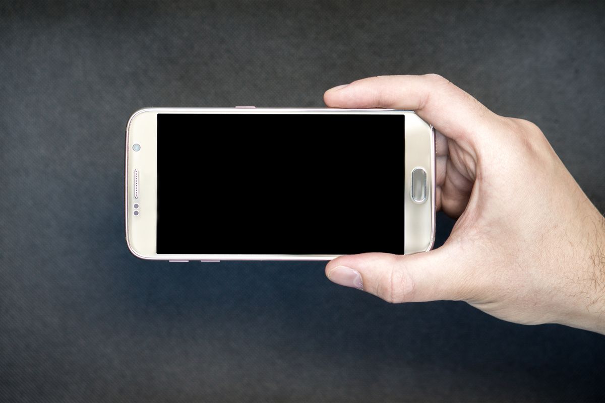 Hand holding an Android phone with a blank screen, illustrating a predictive back gesture animation in Jetpack Compose