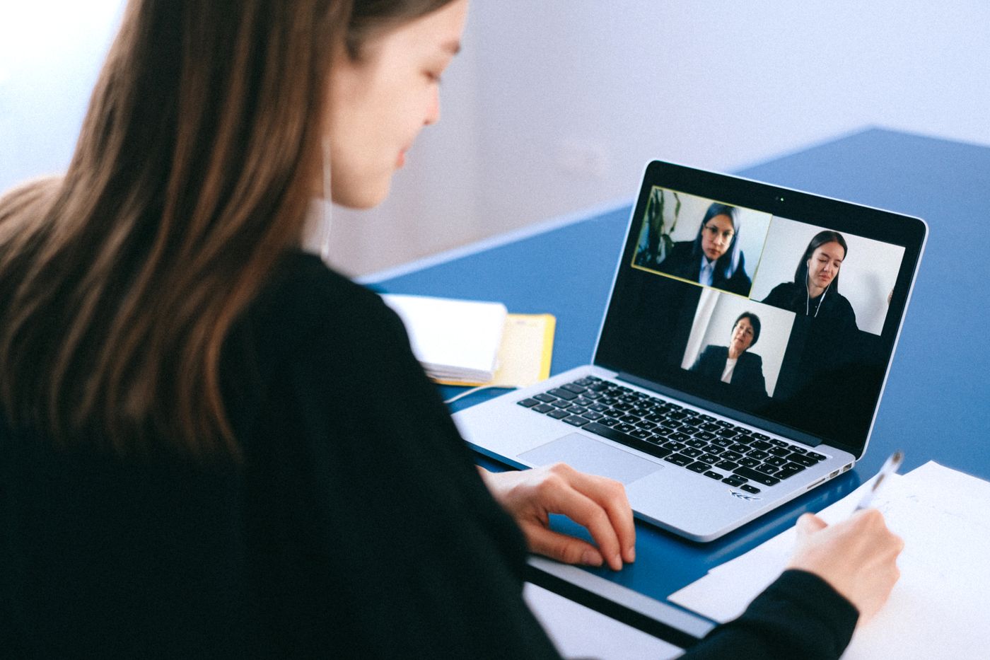 A person taking notes during a video call, the kind of async habit a time zone interview question is testing for