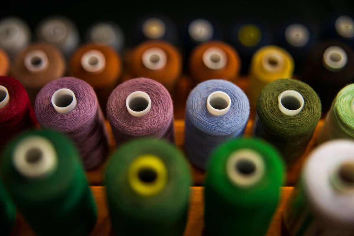 Rows of colored thread spools, representing Kotlin coroutine dispatchers and threads in a withContext(Dispatchers.IO) call