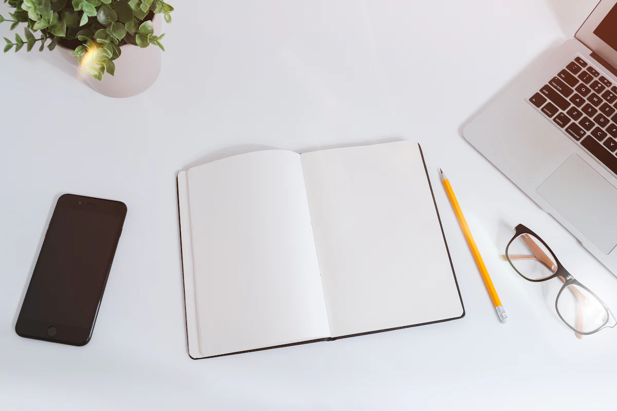 Blank notebook, pencil and phone on a white desk, for planning how to reapply after a failed interview